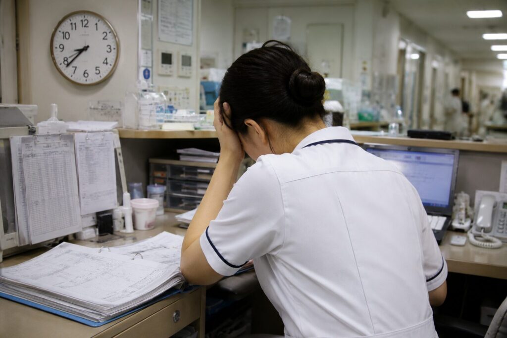 病棟勤務で忙しく疲れた様子の看護師の後ろ姿