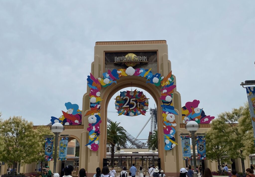 UNIVERSAL STUDIOS JAPANのロゴがあるアーチ型のゲート。カラフルな25周年の装飾と「25th」の飾りが付いている