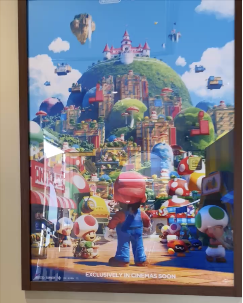 額に入って壁に飾られた、キノコ王国の街を歩くマリオとキノピオたちが描かれたポスター