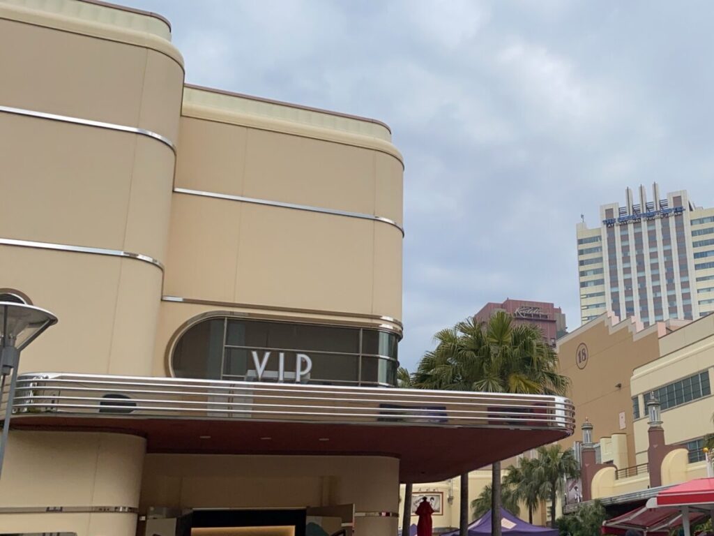 「VIP」の文字が入った、丸みのあるクリーム色の建物。奥にヤシの木とホテルが見える