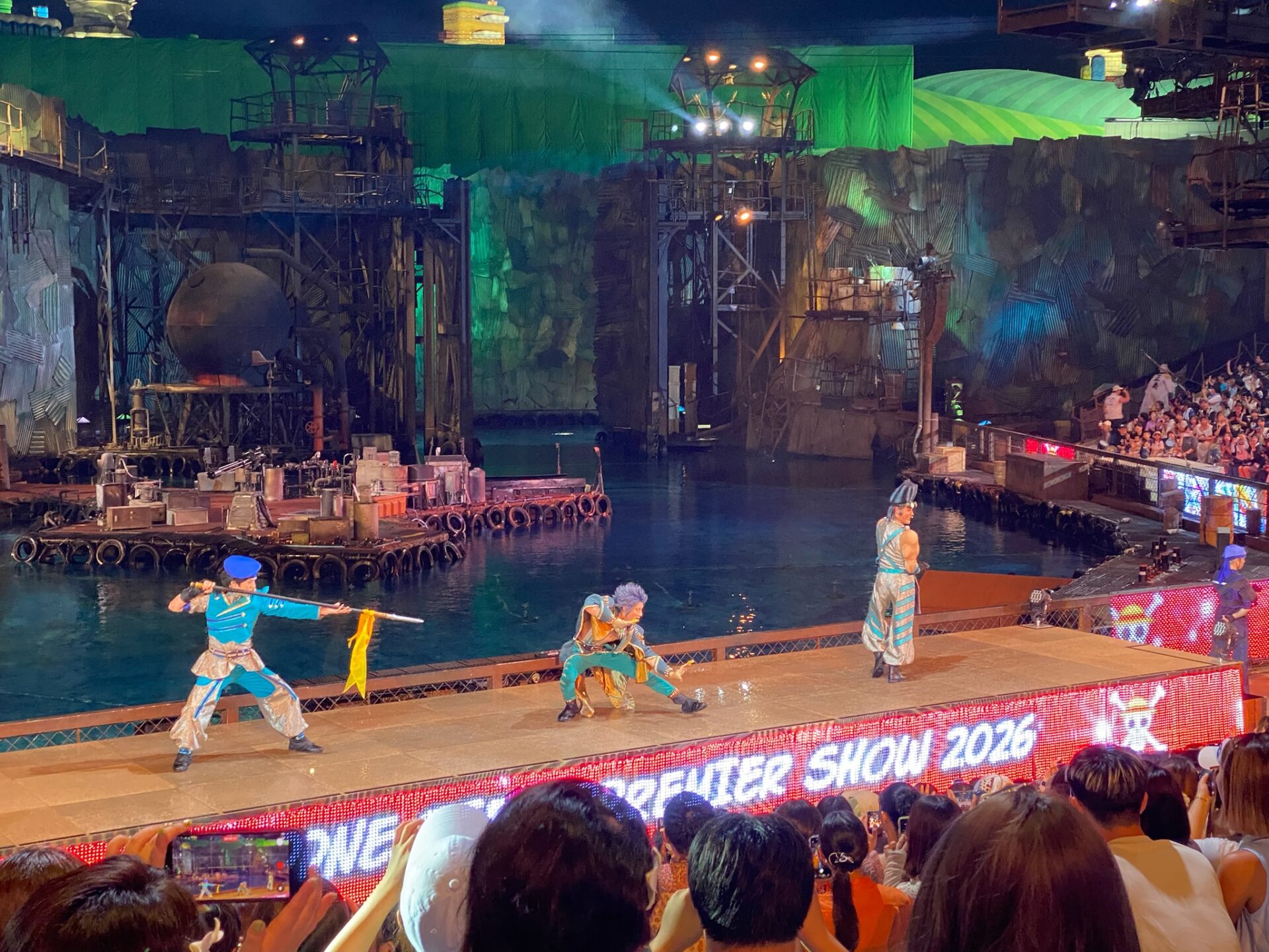 「ONE PIECE PREMIER SHOW 2026」の電光表示があるステージの上で構えをとる3人のキャラクター。中央で低く構えているのがベンディガー