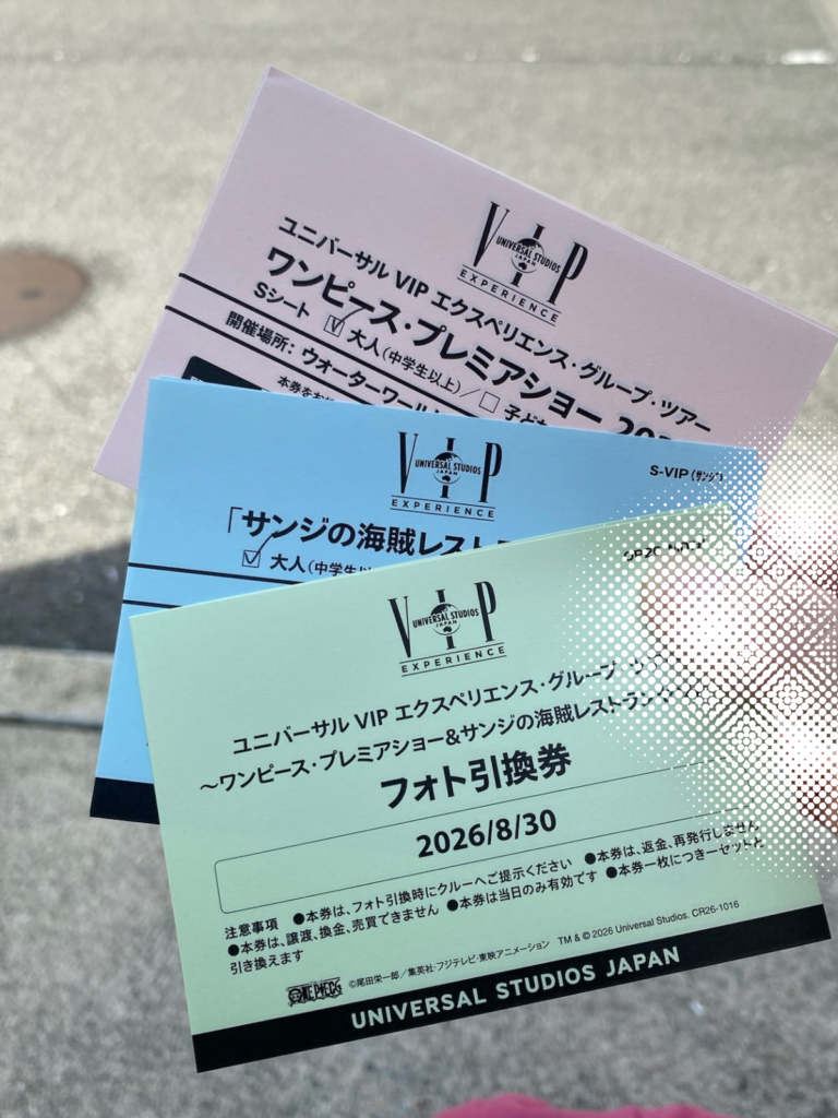 ワンピース・プレミアショーのSシート券、サンジの海賊レストランの券、フォト引換券（2026/8/30）の3枚のチケットを手に持っている