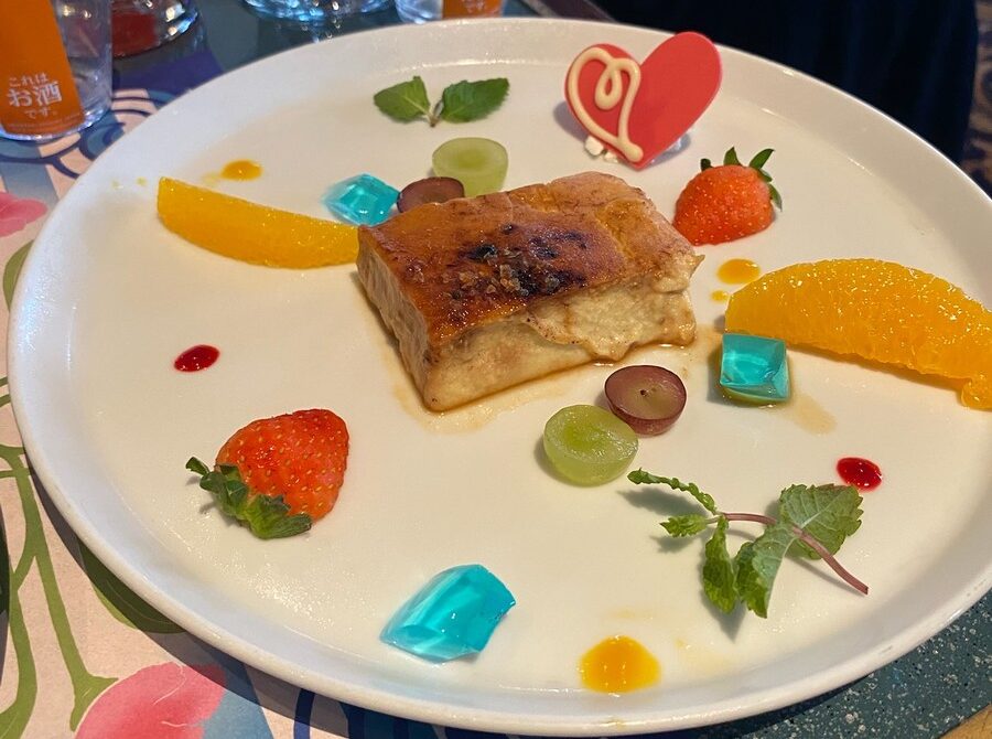 ケーキにイチゴやオレンジ、青いゼリーを添えたデザートの皿