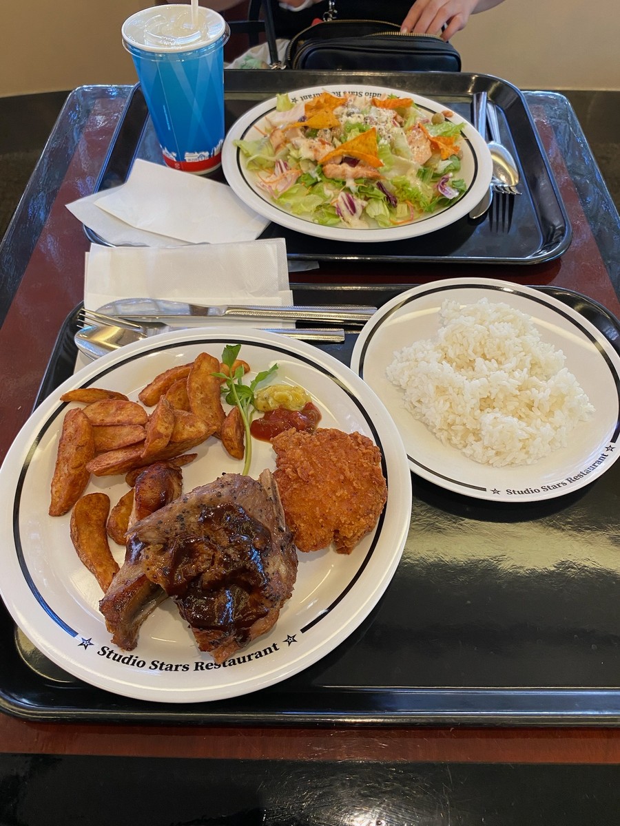 Studio Stars Restaurantの皿にのったポークリブ、ポテト、ライス、サラダとドリンク