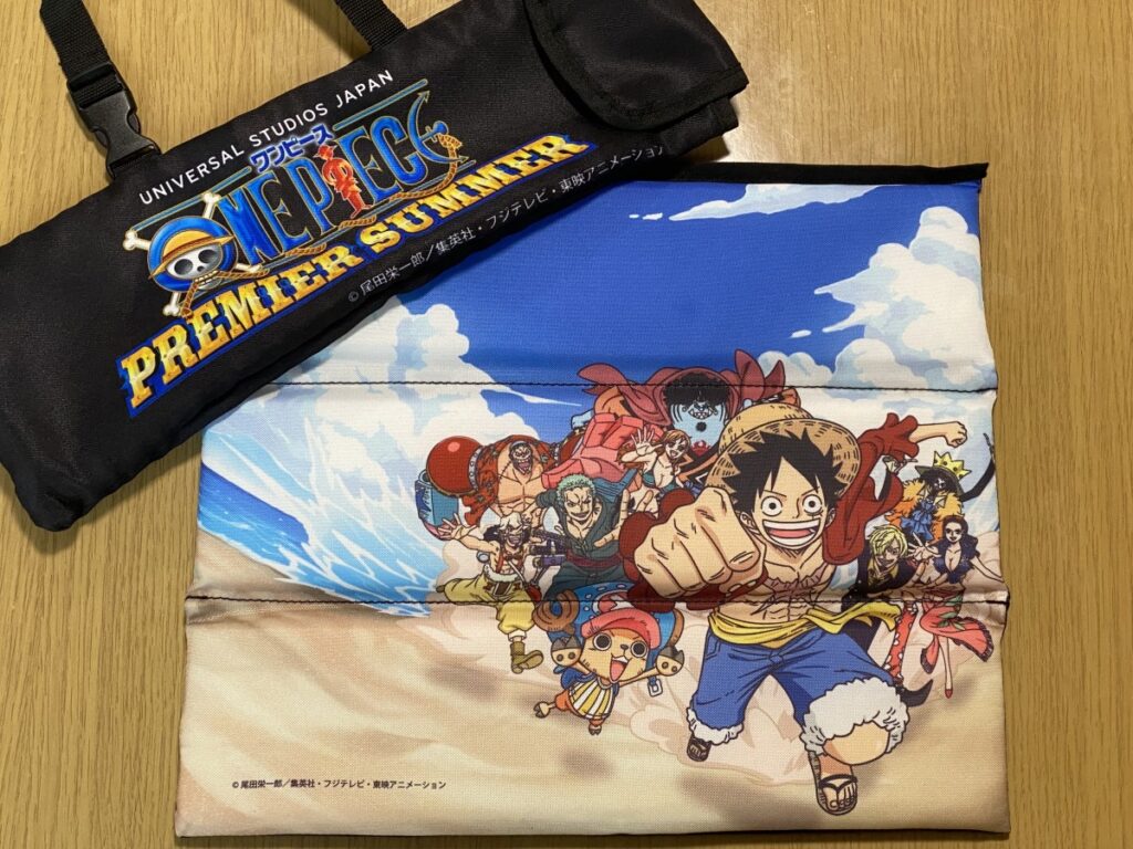 麦わらの一味が描かれたクッションと、ONE PIECE PREMIER SUMMERのロゴが入った黒いケース