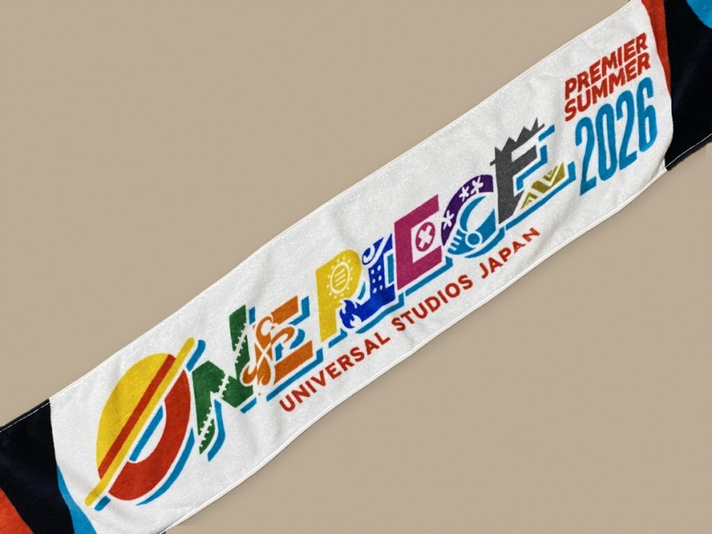 ONE PIECEのロゴとPREMIER SUMMER 2026の文字が入ったマフラータオルを広げたところ