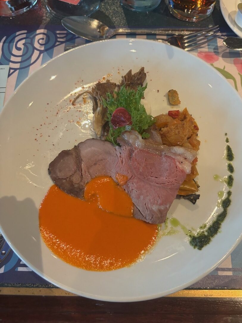 肉料理にオレンジ色のソースを添えたメインの皿