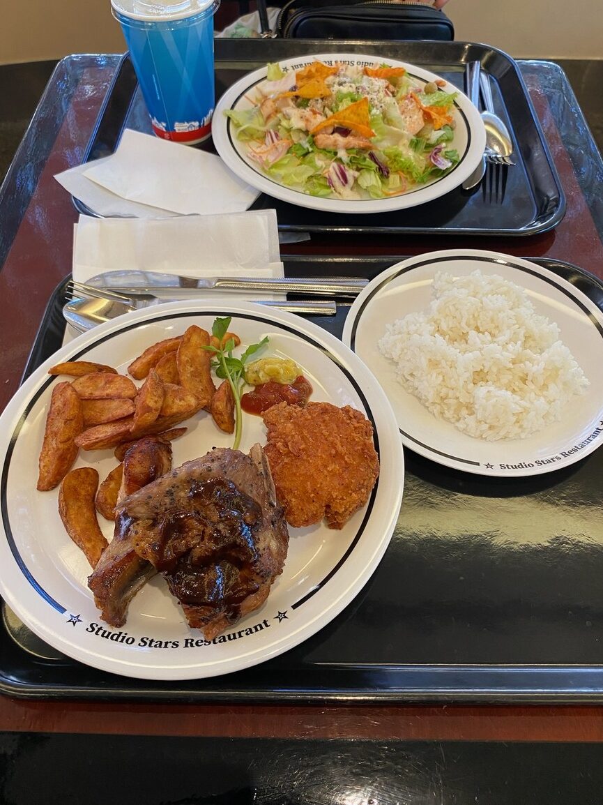 Studio Stars Restaurantの皿にのったポークリブ、ポテト、ライス、サラダとドリンク